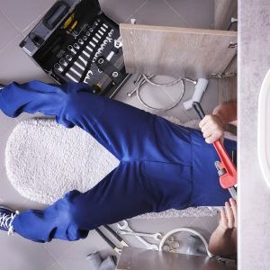 Plumber repairing sink pipes in kitchen
